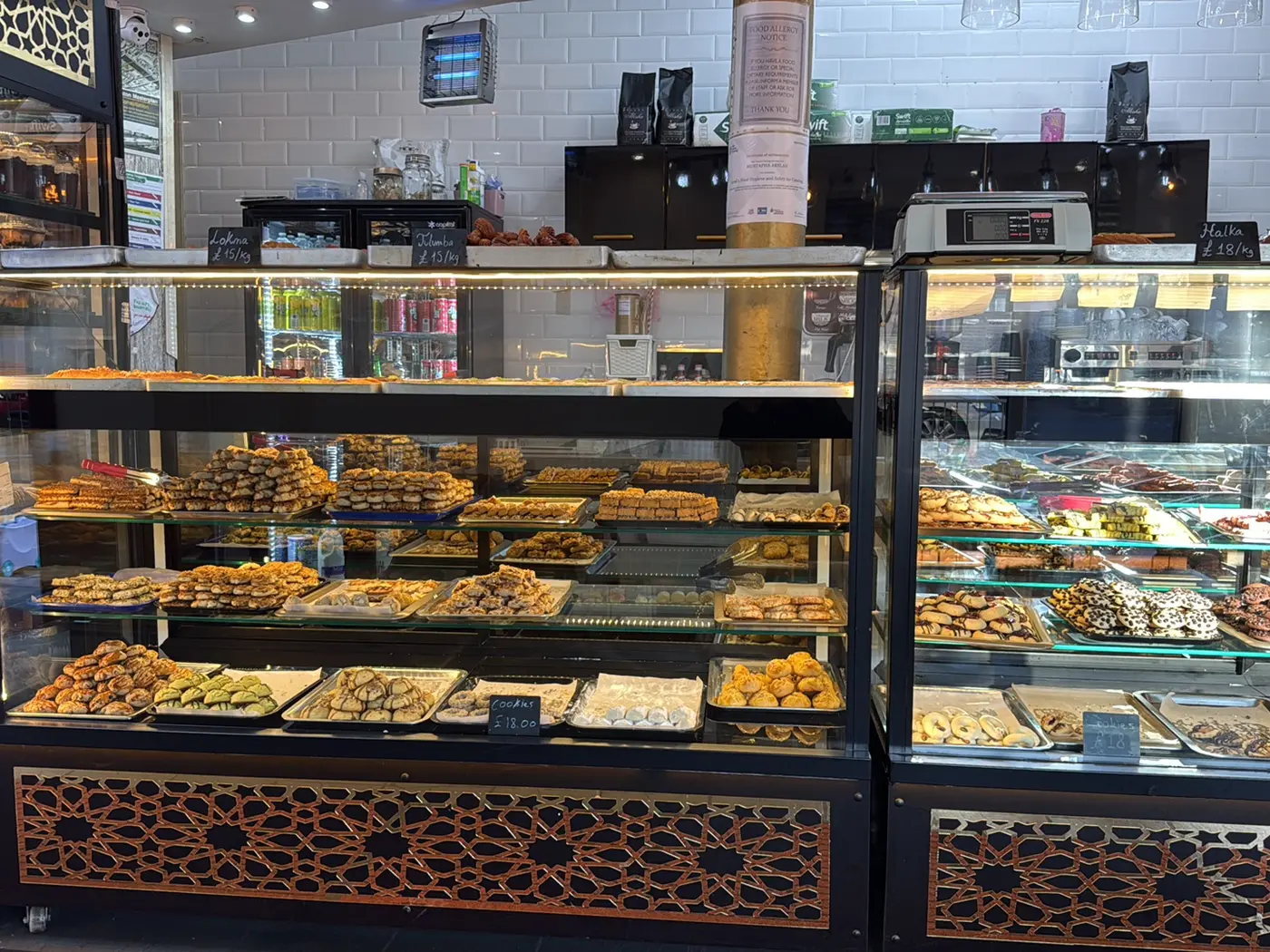Istanbul Cakes and Baklavas shop interior with twin black-and-gold display cases, chalkboard menu boards and copper lattice trim